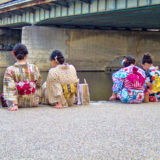 Girls sitting at river bank Kyoto